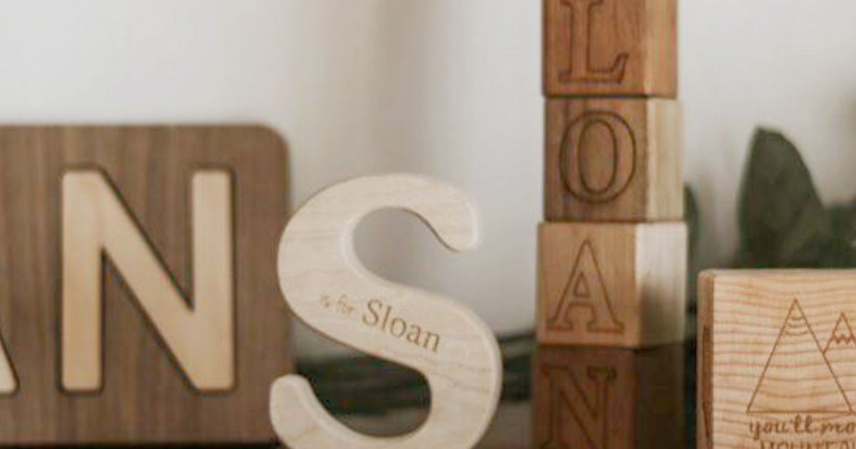A beautiful shelf display of Smiling Tree Toys — personalized wooden blocks, name puzzles, and letter teethers designed for mindful, plastic-free play.
